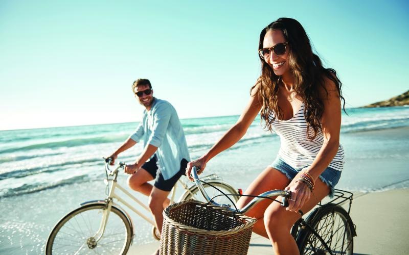 a man and woman riding bikes on a beach