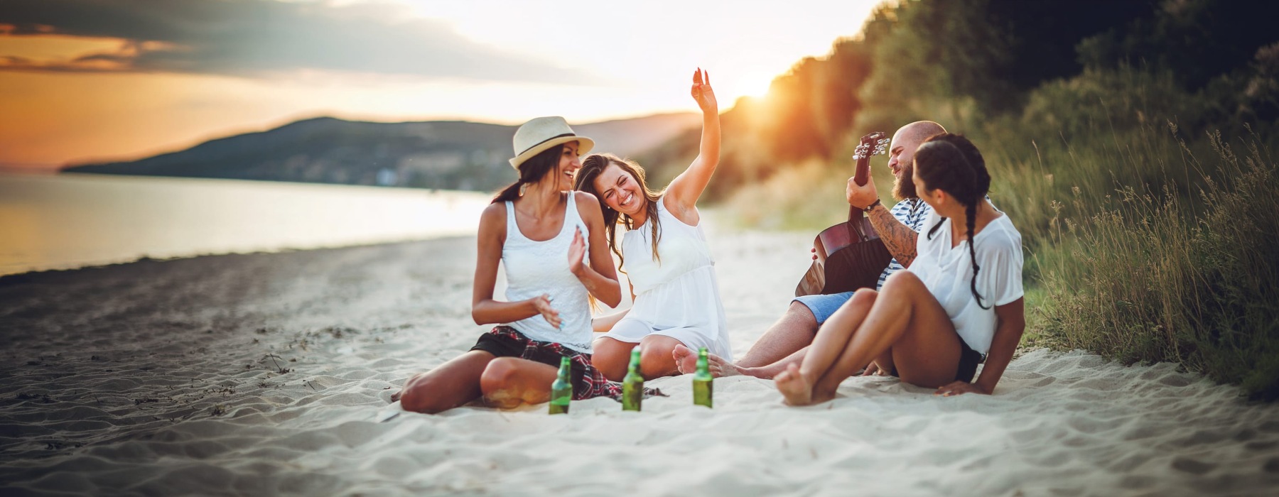 three friends on a beach at sunset