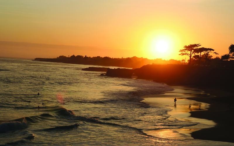 a beach with a body of water and a sunset