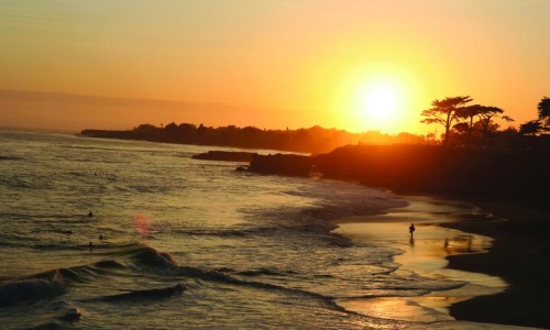 a beach with a body of water and a sunset